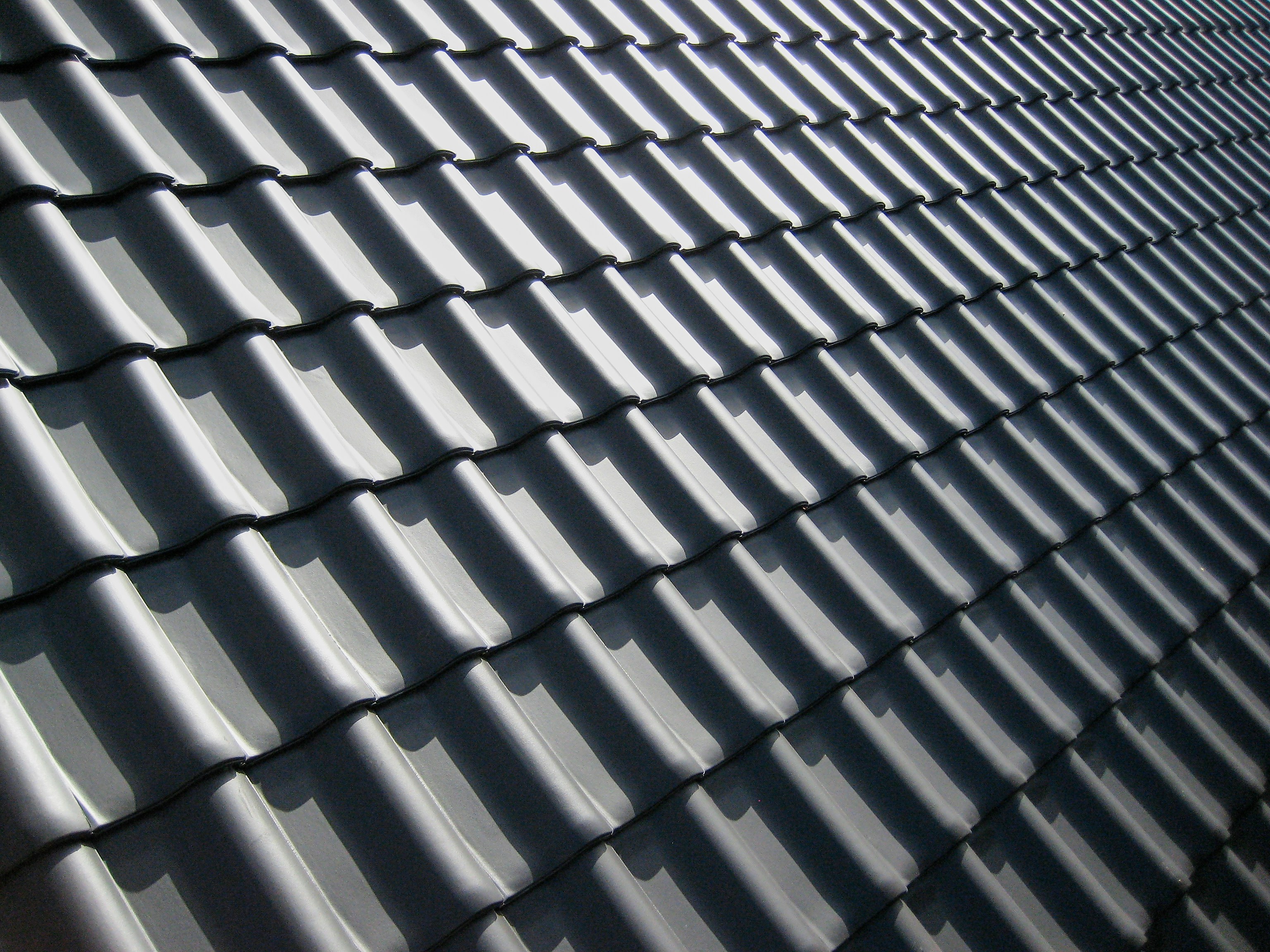 Close-up of new charcoal-grey tile roofing in sunlight